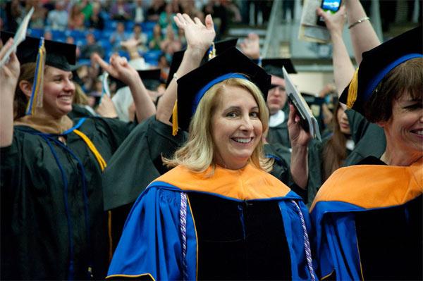 A non-traditional student, older than a typical college student, wearing academic regalia at a graduation ceremony